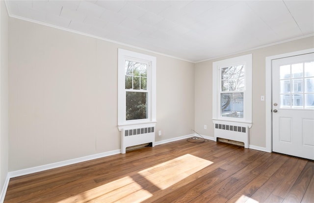 foyer entrance with hardwood / wood-style floors, ornamental molding, and radiator