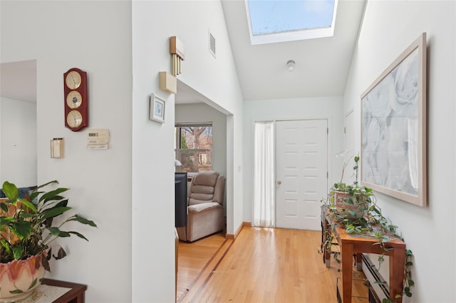 foyer featuring light hardwood / wood-style flooring and lofted ceiling with skylight