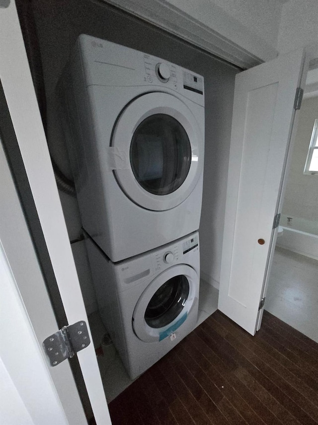 washroom with stacked washing maching and dryer and dark wood-type flooring