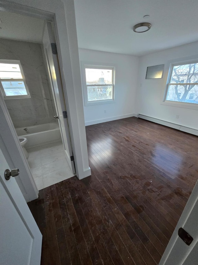 bathroom featuring hardwood / wood-style flooring, toilet, tiled shower / bath, and a baseboard heating unit