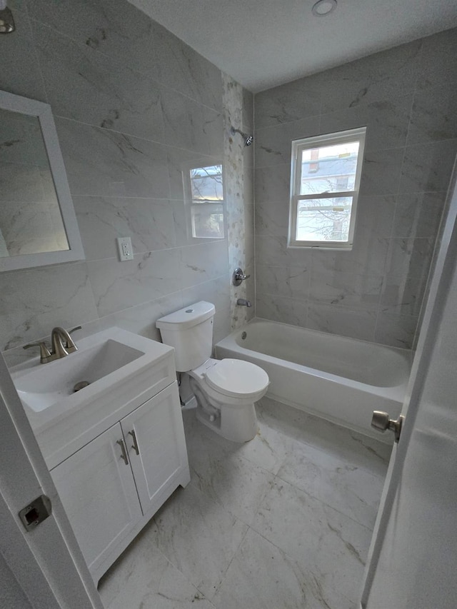 full bathroom featuring vanity, tiled shower / bath combo, toilet, and tile walls