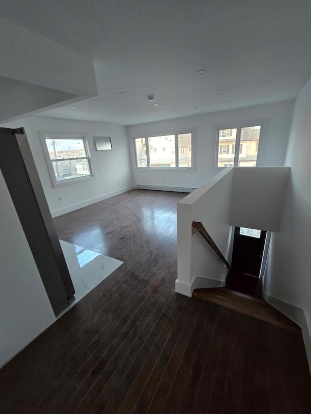 unfurnished living room featuring dark wood-type flooring and a healthy amount of sunlight