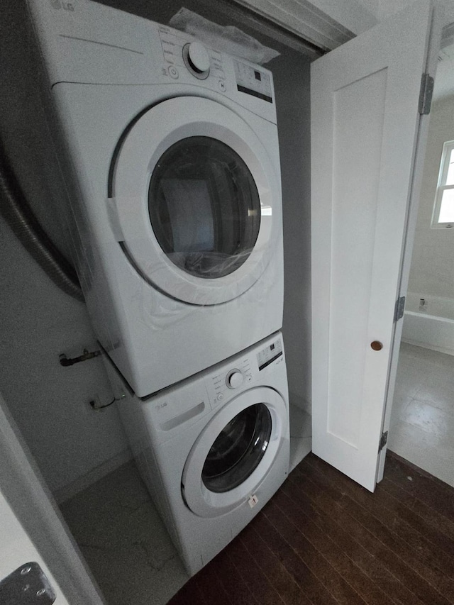 laundry area featuring dark hardwood / wood-style flooring and stacked washer and dryer