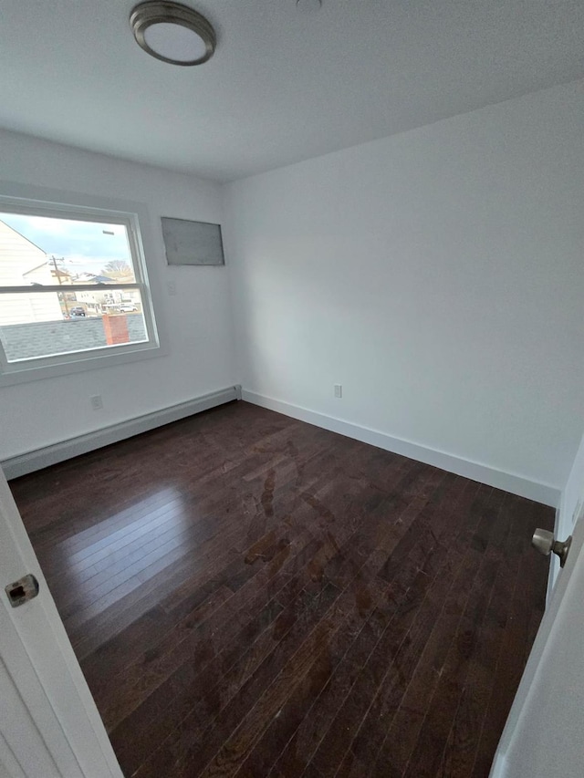 spare room featuring dark hardwood / wood-style floors and baseboard heating