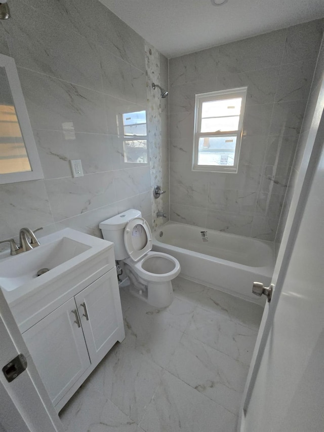 full bathroom with vanity, toilet, tiled shower / bath, and tile walls