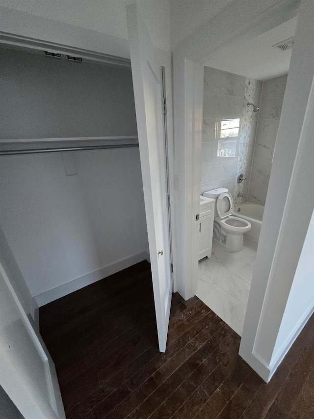 full bathroom featuring vanity, wood-type flooring, tiled shower / bath combo, and toilet