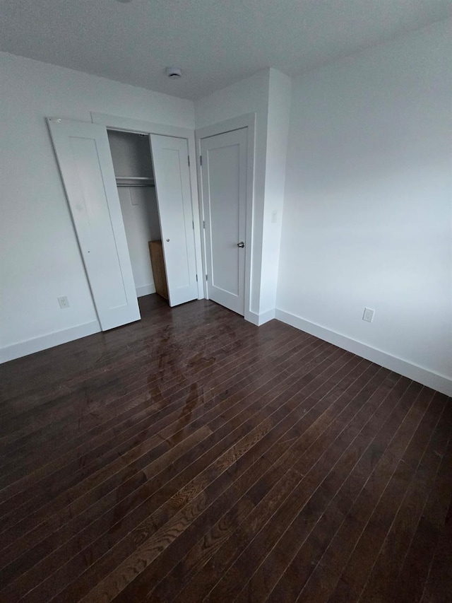 unfurnished bedroom with a closet and dark wood-type flooring