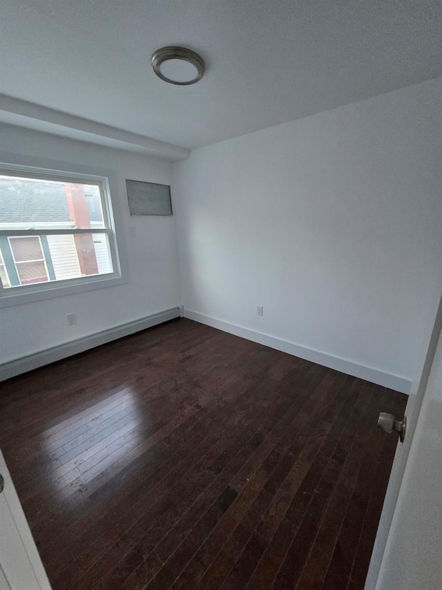 spare room with dark wood-type flooring and a baseboard radiator