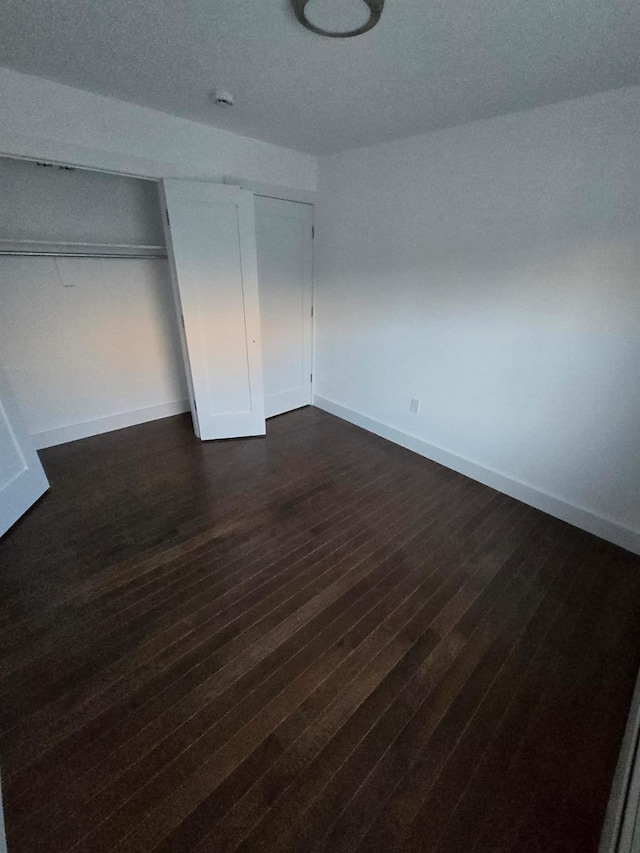 unfurnished bedroom featuring dark hardwood / wood-style flooring and a closet