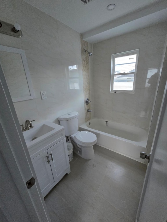 full bathroom featuring toilet, vanity, tile walls, and tiled shower / bath