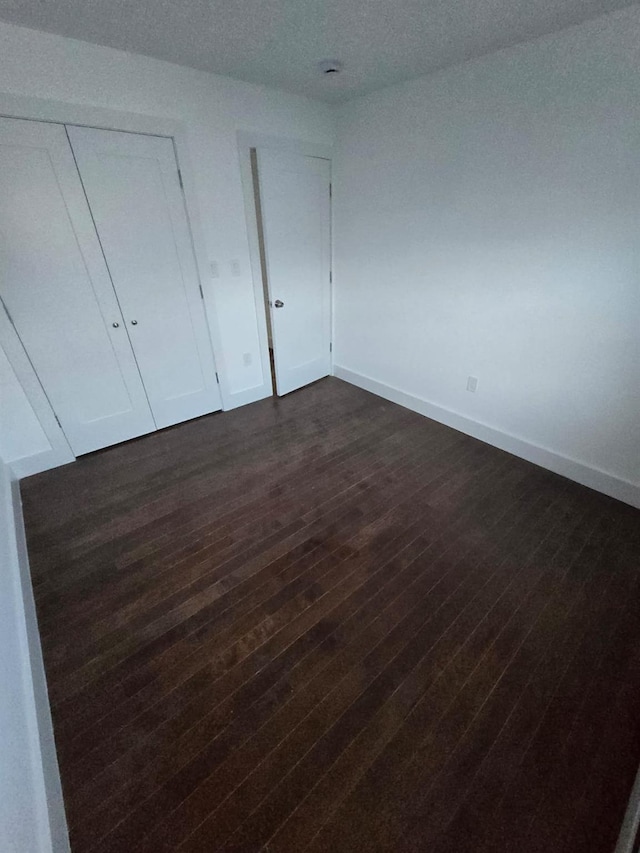 unfurnished bedroom with dark hardwood / wood-style flooring and a closet