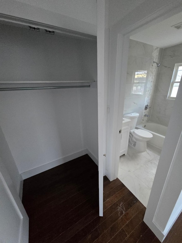 full bathroom with vanity, wood-type flooring, tiled shower / bath combo, and toilet