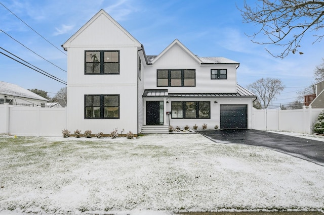 modern inspired farmhouse featuring a standing seam roof, fence, driveway, and metal roof