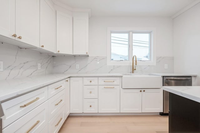 kitchen featuring tasteful backsplash, white cabinetry, sink, and light stone countertops