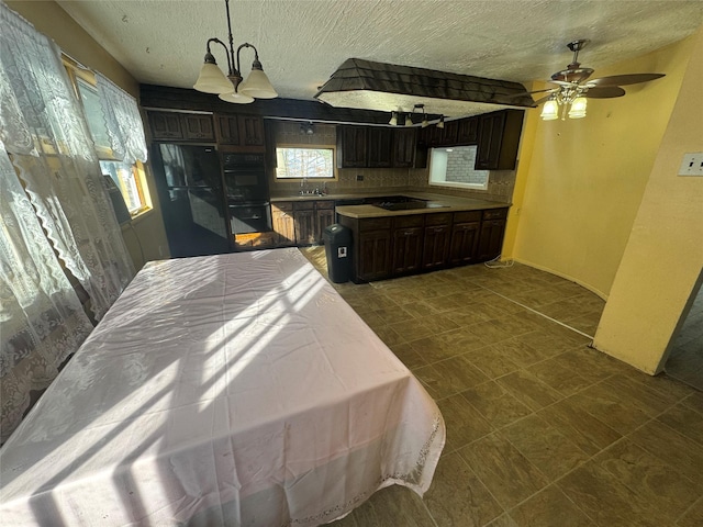 kitchen featuring sink, hanging light fixtures, dark brown cabinets, black appliances, and ceiling fan with notable chandelier