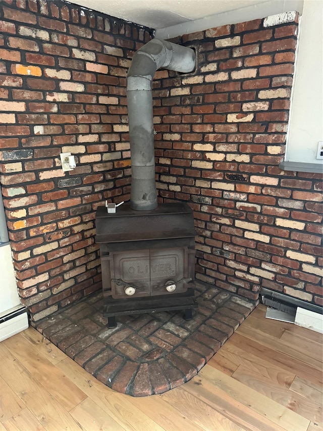 room details with baseboard heating, a wood stove, and wood-type flooring