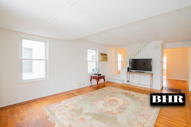 unfurnished living room featuring hardwood / wood-style floors and a wall mounted air conditioner