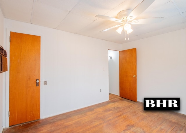 spare room with a drop ceiling, hardwood / wood-style flooring, and ceiling fan