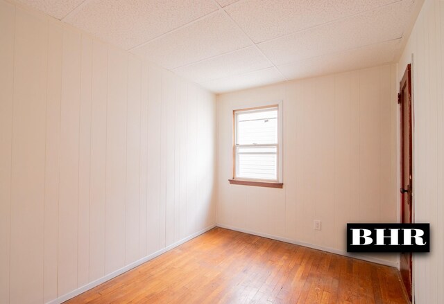 unfurnished room featuring hardwood / wood-style floors and wood walls