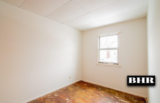 empty room with hardwood / wood-style flooring and a drop ceiling