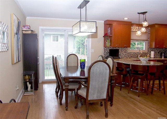 dining area featuring sink, ornamental molding, and light wood-type flooring