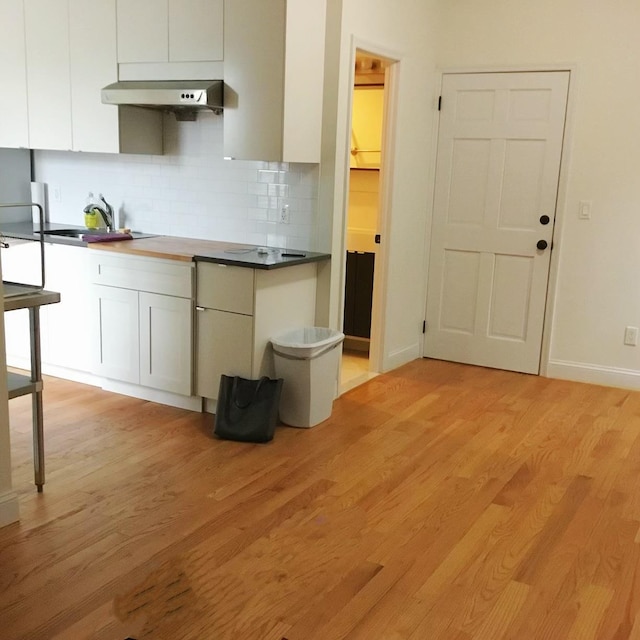 kitchen with sink, butcher block counters, tasteful backsplash, light hardwood / wood-style floors, and white cabinets