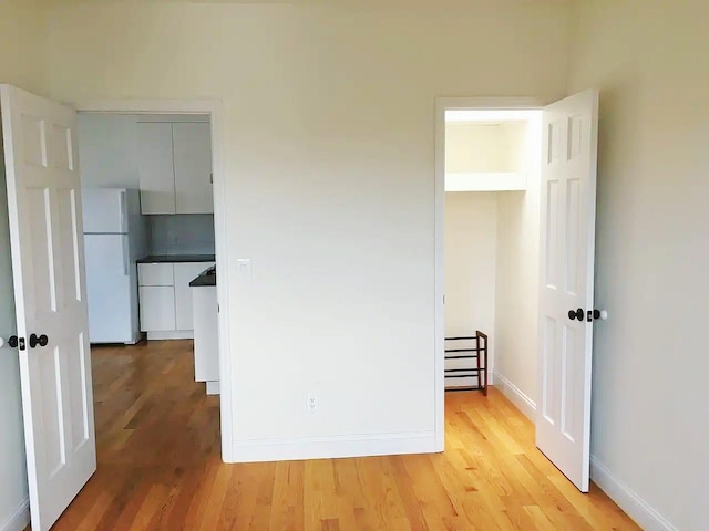 unfurnished bedroom featuring white refrigerator and light hardwood / wood-style floors