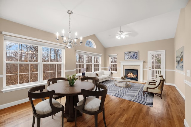 dining space featuring light hardwood / wood-style floors, lofted ceiling, and ceiling fan with notable chandelier