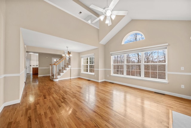 unfurnished living room with high vaulted ceiling, ceiling fan with notable chandelier, and hardwood / wood-style flooring