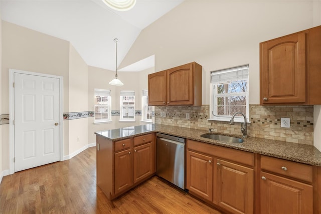 kitchen with vaulted ceiling, kitchen peninsula, pendant lighting, sink, and stainless steel dishwasher