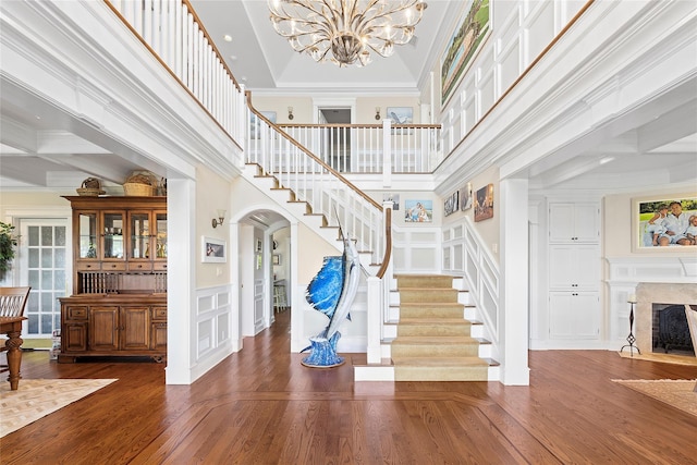 entrance foyer featuring coffered ceiling, an inviting chandelier, crown molding, a towering ceiling, and beamed ceiling