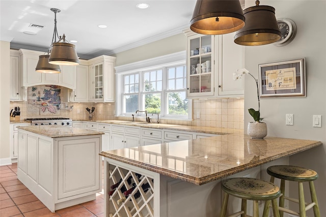 kitchen featuring a breakfast bar, tasteful backsplash, light tile patterned flooring, light stone counters, and kitchen peninsula