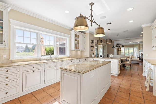 kitchen featuring tasteful backsplash, crown molding, sink, a center island, and hanging light fixtures