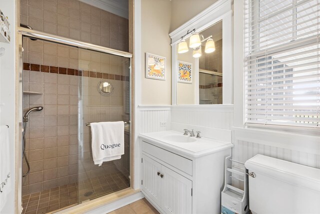 bathroom with tile patterned flooring, vanity, toilet, and a shower with shower door