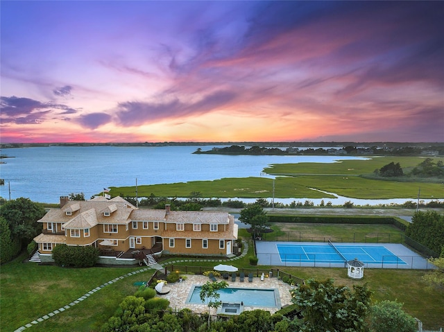 aerial view at dusk featuring a water view