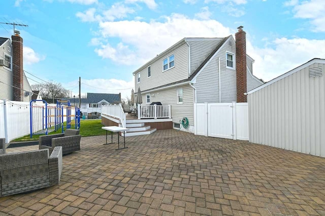 rear view of house with a wooden deck, outdoor lounge area, a patio, and a trampoline