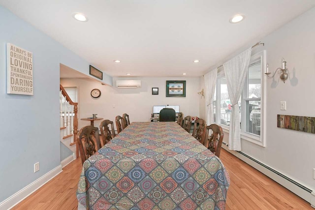 dining room featuring baseboard heating, light hardwood / wood-style flooring, and a wall unit AC