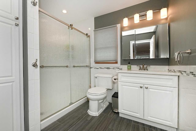 bathroom featuring vanity, a shower with shower door, and toilet