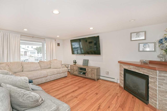 living room featuring a fireplace, light hardwood / wood-style floors, and baseboard heating