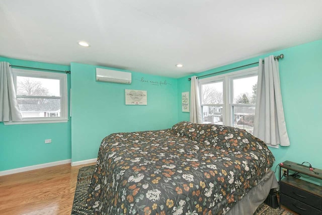 bedroom featuring multiple windows, light hardwood / wood-style floors, and a wall mounted AC