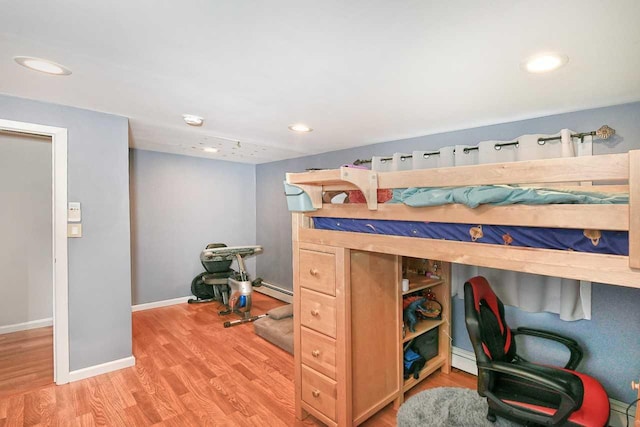 bedroom with light hardwood / wood-style floors and a baseboard heating unit