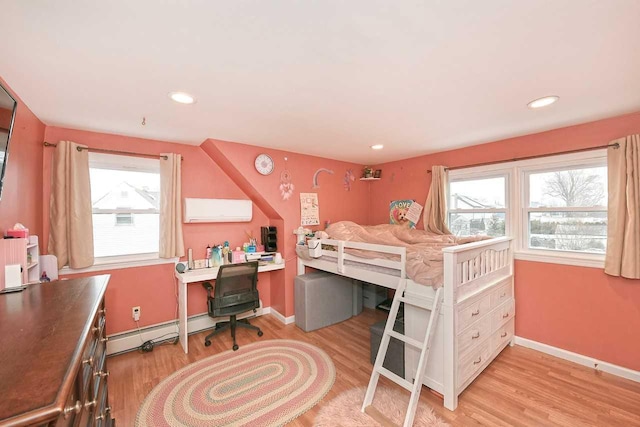 bedroom featuring light hardwood / wood-style floors, multiple windows, and a baseboard heating unit