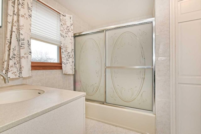 bathroom featuring shower / bath combination with glass door, lofted ceiling, vanity, and tile walls