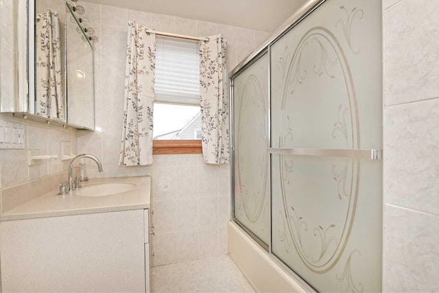 bathroom with shower / bath combination with glass door, vanity, and tile walls