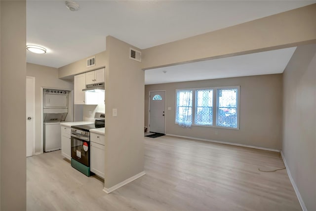 kitchen featuring electric stove, white cabinetry, stacked washer and dryer, and light hardwood / wood-style floors