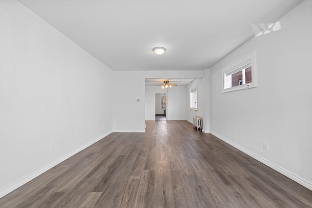 unfurnished living room featuring ceiling fan, radiator, and dark wood-type flooring