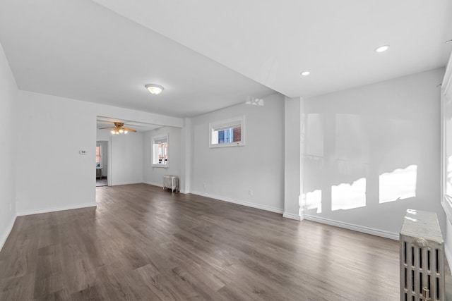 unfurnished living room featuring dark hardwood / wood-style flooring, radiator, and ceiling fan