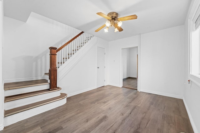 stairway featuring a healthy amount of sunlight, hardwood / wood-style flooring, and ceiling fan