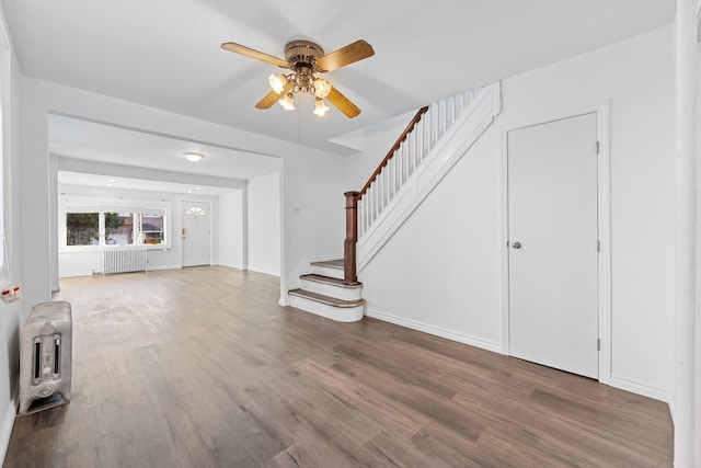 unfurnished living room featuring wood-type flooring, radiator heating unit, and ceiling fan