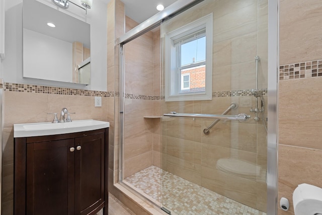 bathroom featuring walk in shower, vanity, and tile walls